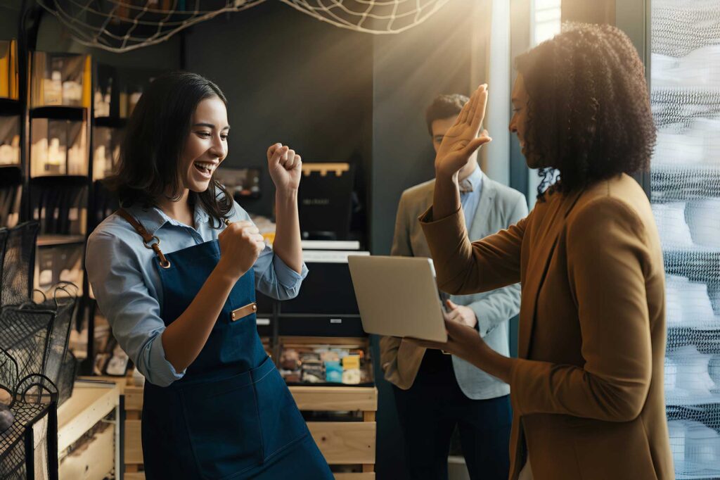 A young female business owner high fiving her colleagues after their professional website launch.